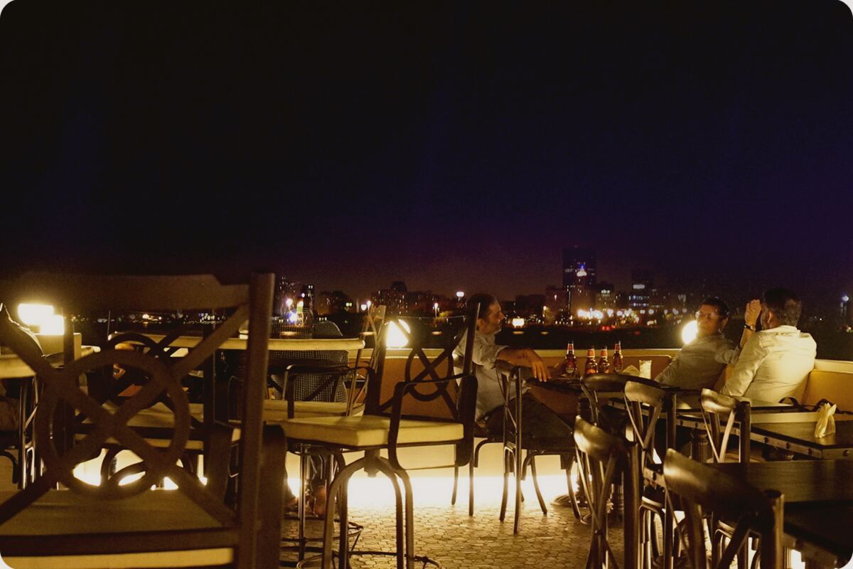 The rooftop terrace at Bayview Café in Colaba, its tables lit at dusk above the harbour