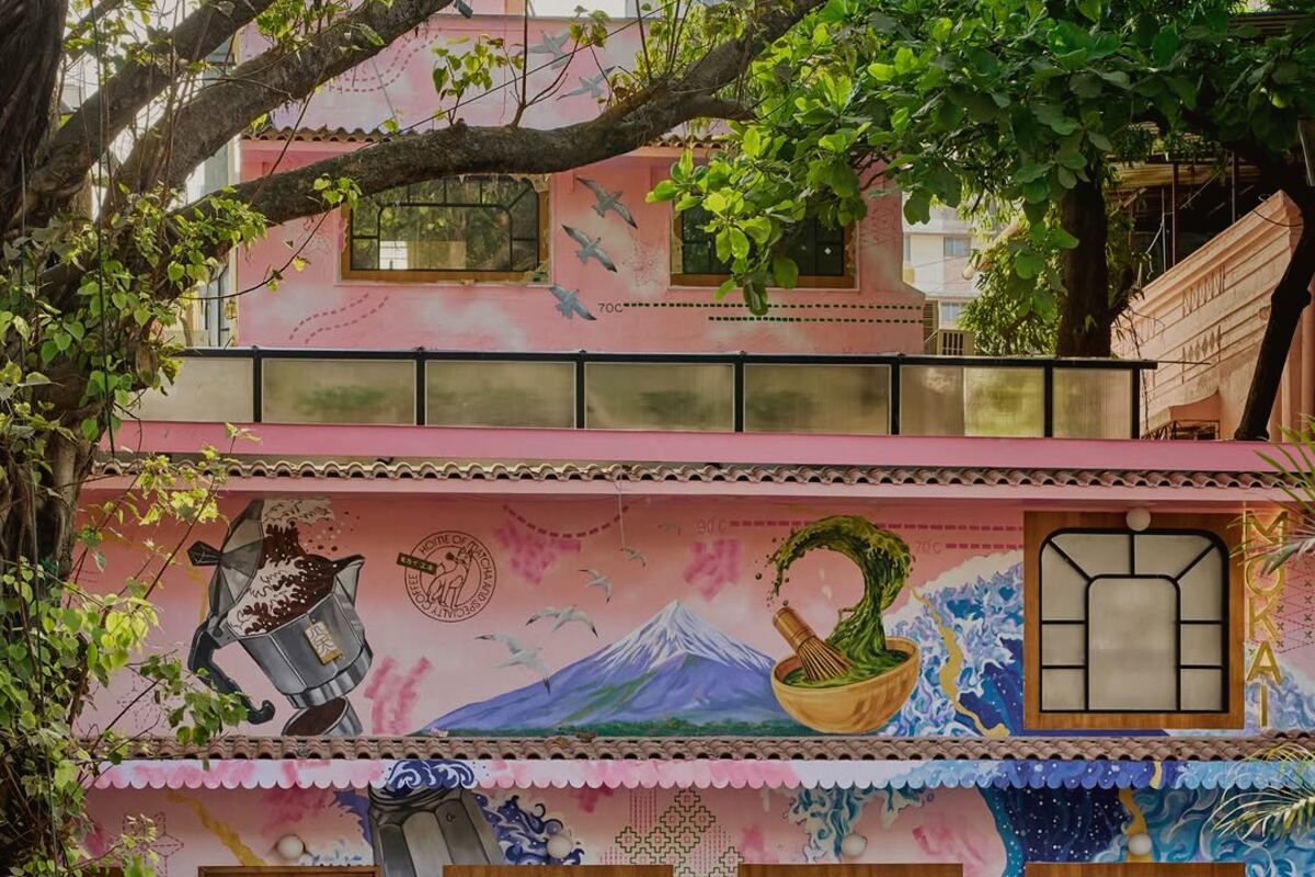 Mokai's pink facade on Pali Hill, Bandra West, painted with murals and screened by a tree