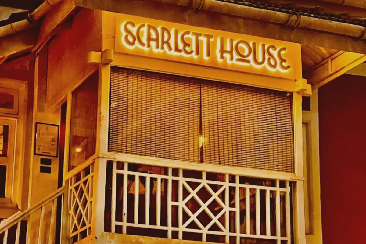 The lit Scarlett House sign above the first-floor balcony of the Red Bungalow in Pali Village, Bandra West, at dusk