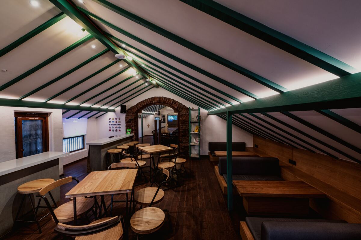 The pitched-roof room at Subko's Mary Lodge in Bandra West, with communal timber tables and stools under exposed rafters